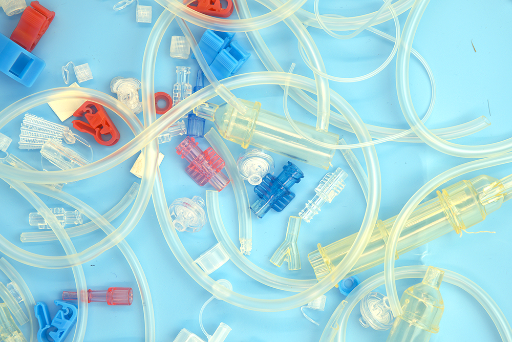Different parts of plastic medical devices are strewn on a blue background.