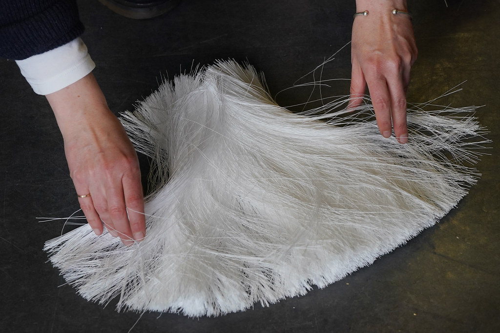 Hands positioning white fibres from a dialysis cartridge on a dark floor