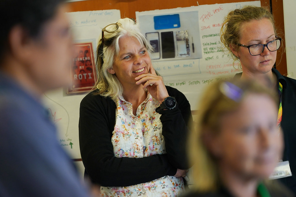 Anne Kviem-Lee smiling as she observes a collaborator posing as part of a living exhibition