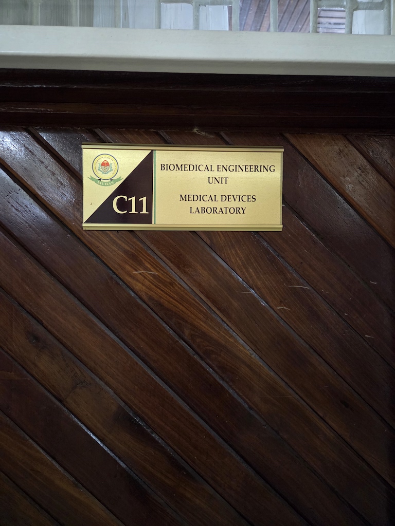 A brass plaque reading biomedical research unit is fixed to a dark wooden wall that's been fixed in diagonal panel.