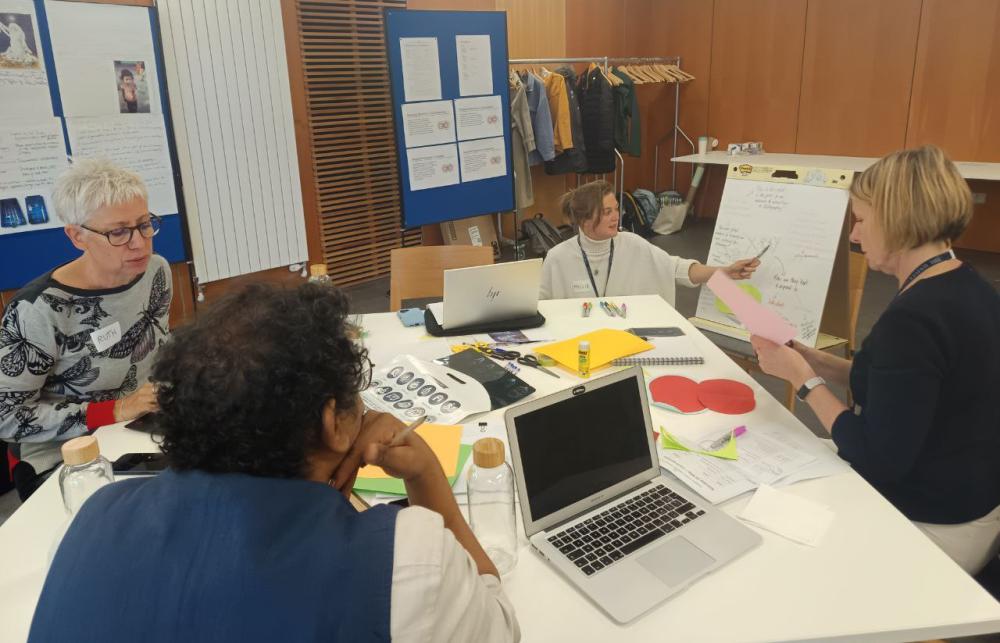 Team members workshopping the factors leading to the disposability of X-rays on a busy table with lots of papers and laptops.