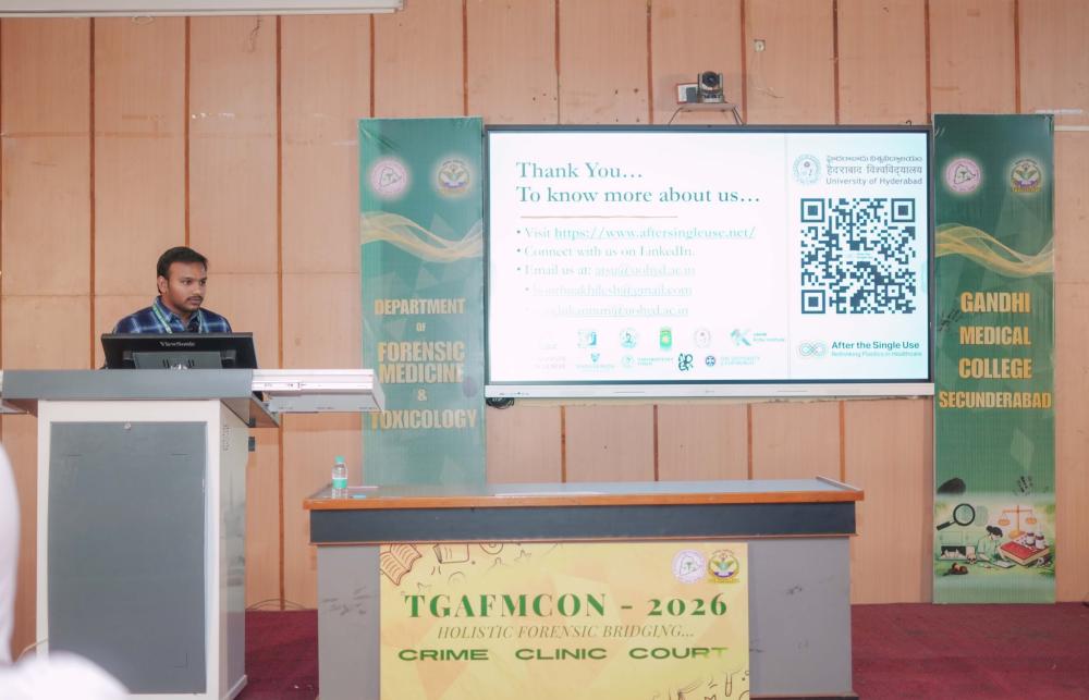 After the Single Use researcher Akhilesh Bonthu presenting a paper at a lecture in a room with wooden panelling behind him and a projector screen. 