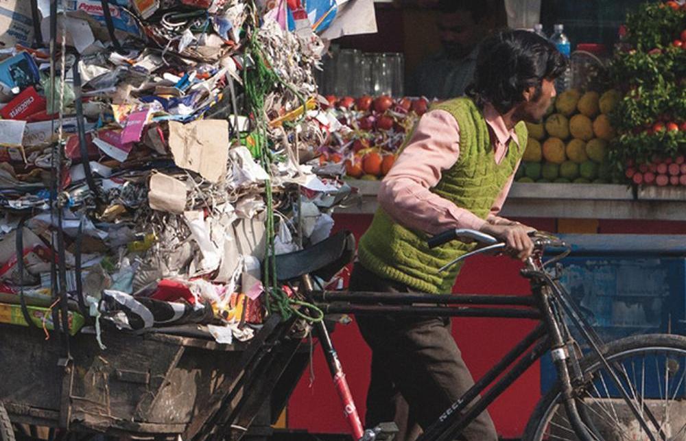 Book cover of 'Waste of a Nation' with an image of a cyclist with a large bundle of garbage on the back of the bike.