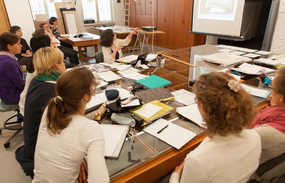 A group of researchers group around a table to see a presentation of the screen infront of them. 