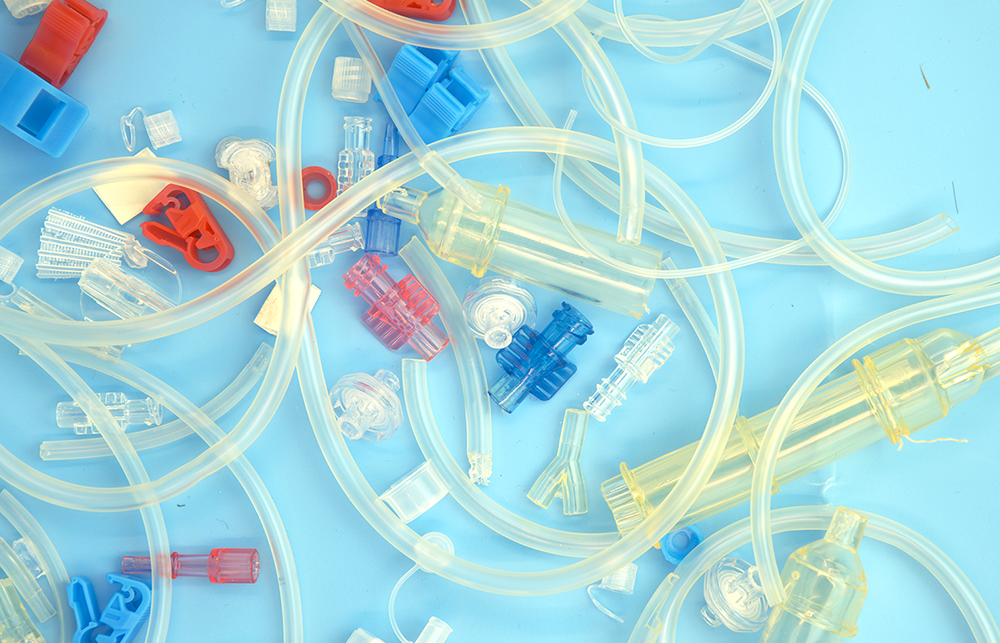 Different parts of plastic medical devices are strewn on a blue background. 