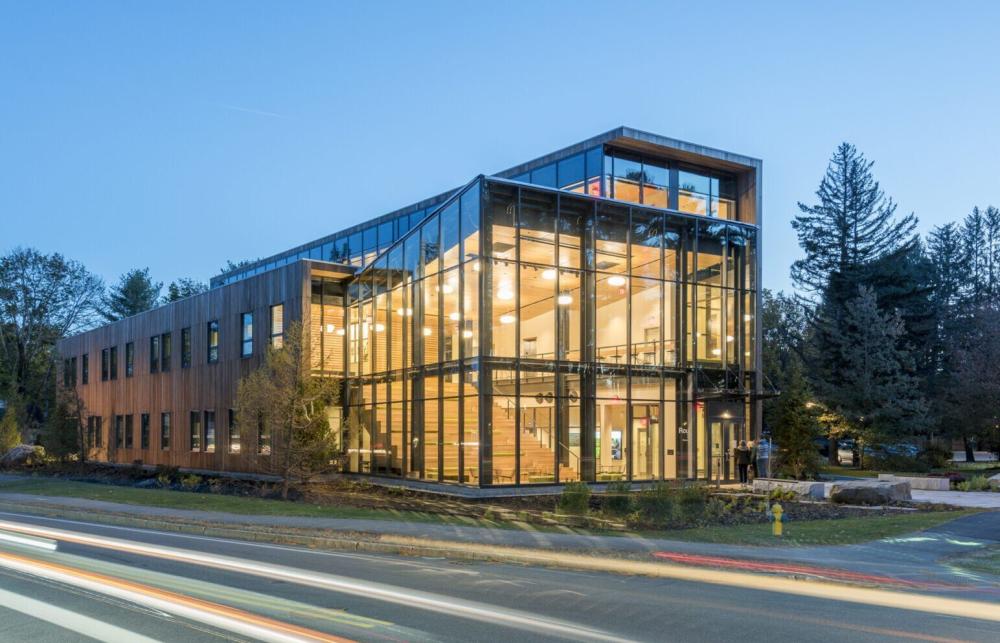 A nighttime image of the Department of Environmental Studies at Bowdoin College with blurred car lights passing on the road nearby. 