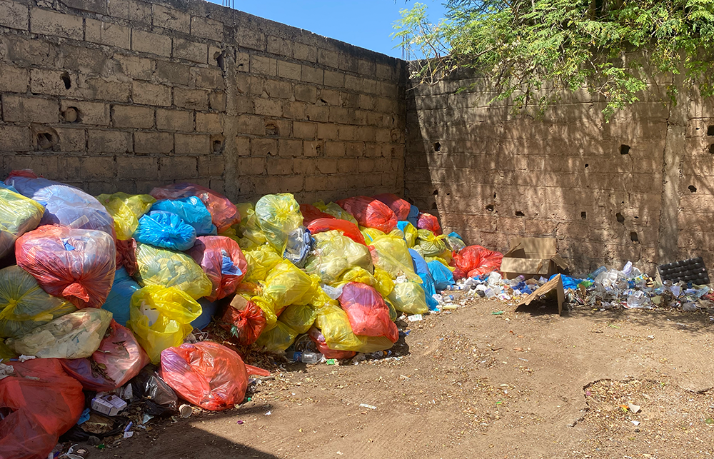 Various medical waste bags are stacked against a wall at Fann Hospital in Dakar, Senegal.