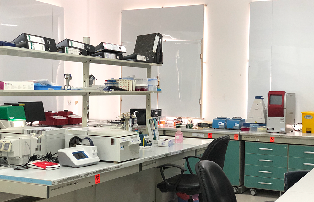 A medical testing room with various apparatus white white walls and blinds over the windows. 