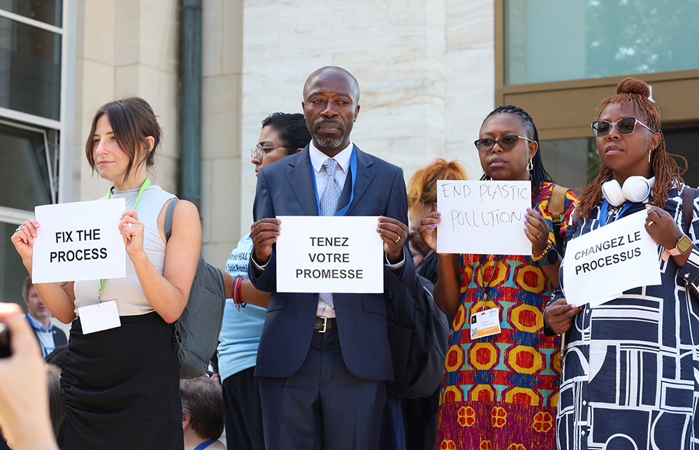 Four protester stand with placards in different languages asking for plastic reforms. 